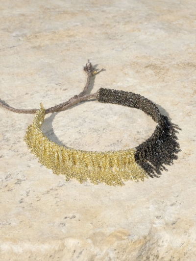 Bracelet en fils d'argent baigné d'or et de ruthénium. Noeud coulissant en fil de soie. Créatrice Parisienne de renommée